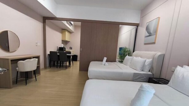 A hotel room with a bed, a desk, a chair, and a dining area in the background. - D'Sara Sentral Condo (Petaling Jaya)