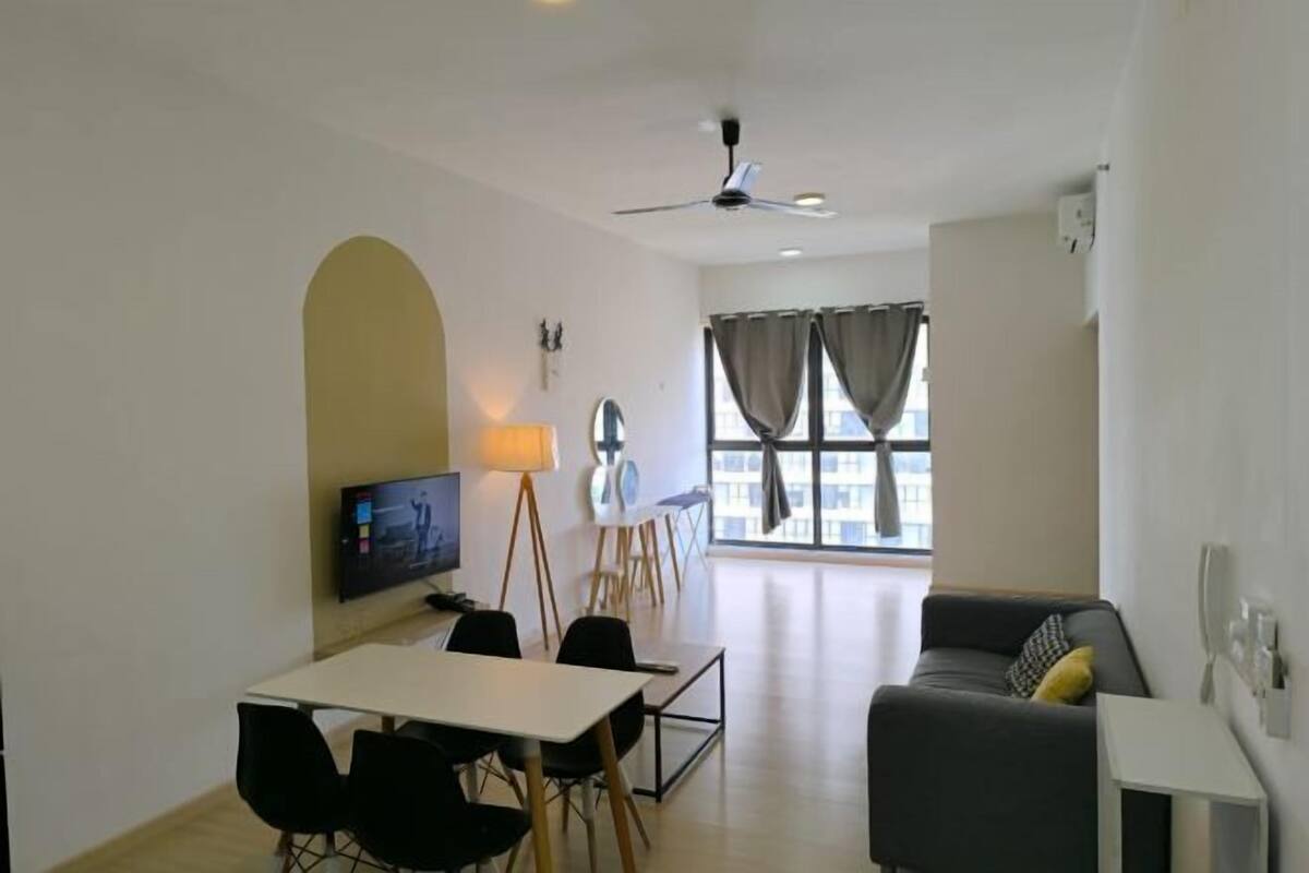 Un salon moderne avec un canapé, une table à manger et des chaises, un téléviseur et un ventilateur de plafond.