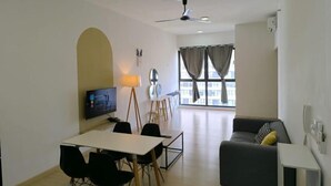 A modern living room with a sofa, a dining table with chairs, a TV, and a ceiling fan. - D'Sara Sentral Condo (Petaling Jaya)