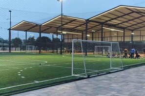 An outdoor sports facility with a soccer field, goalposts, and a covered spectator area.
