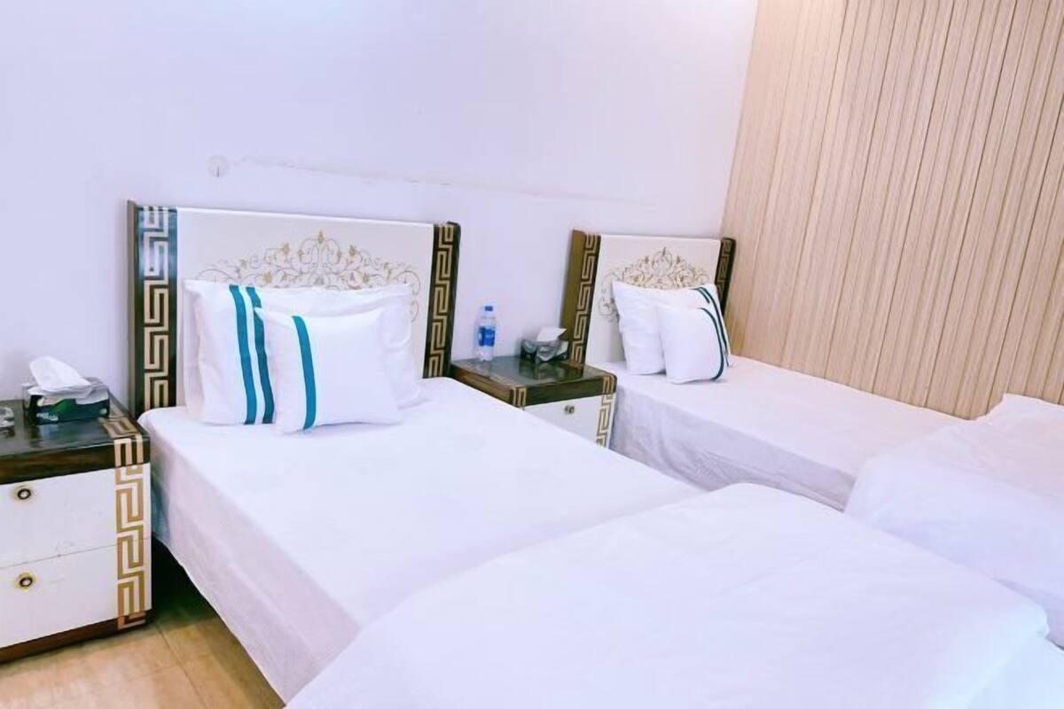 A hotel room with two beds, each with a headboard, bedside tables, and a small table between the beds.