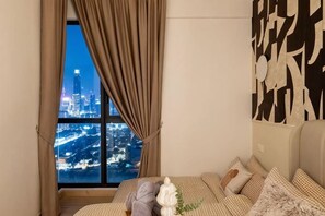 Un dormitorio con vista a la ciudad, una cama con ropa de cama estampada y una pared decorada con arte abstracto.
