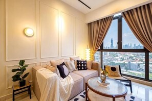 Camera d'albergo moderna con divano, un tavolino, una pianta in vaso e vista sulla città attraverso ampie finestre.