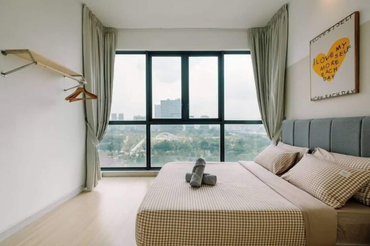 A bedroom with a large window, a bed with a checkered bedspread, a grey headboard, and a wall with a motivational quote.