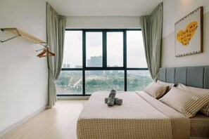 Una camera da letto con un'ampia finestra, un letto con copriletto a quadri, una testiera grigia e una parete con una citazione motivazionale.