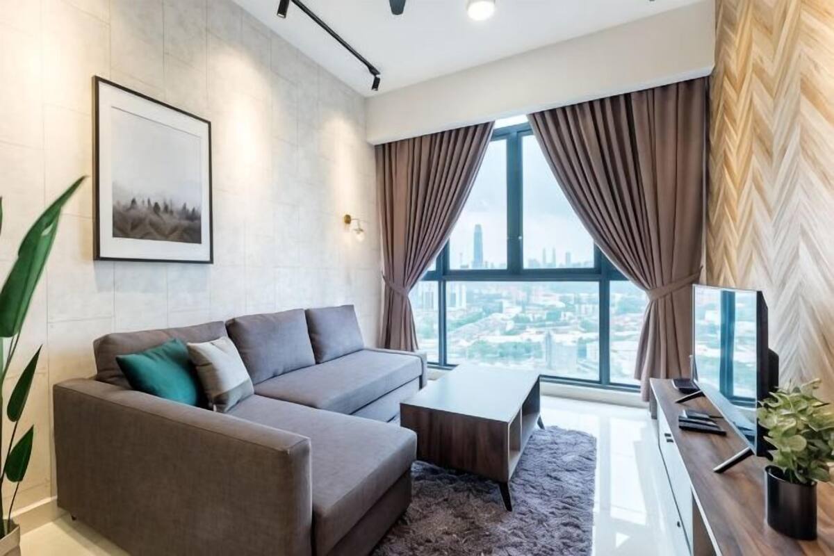 A modern living room with a sofa, coffee table, and a large window with curtains.