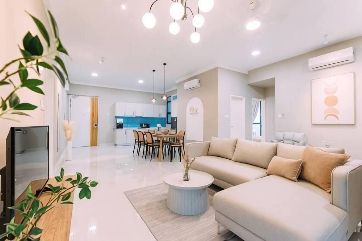A modern living room with a sofa, dining table, and kitchen in the background.