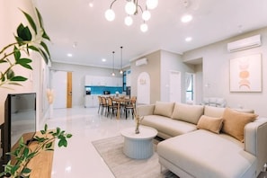 A modern living room with a sofa, dining table, and kitchen in the background.
