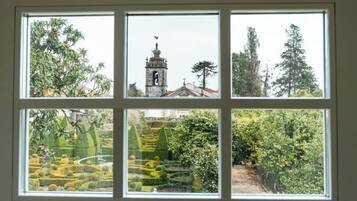 Una finestra de quatre vidres, cada un amb vistes diferents: un arbre, una torre campanar, un bosc dens i un jardí amb formes geomètriques.