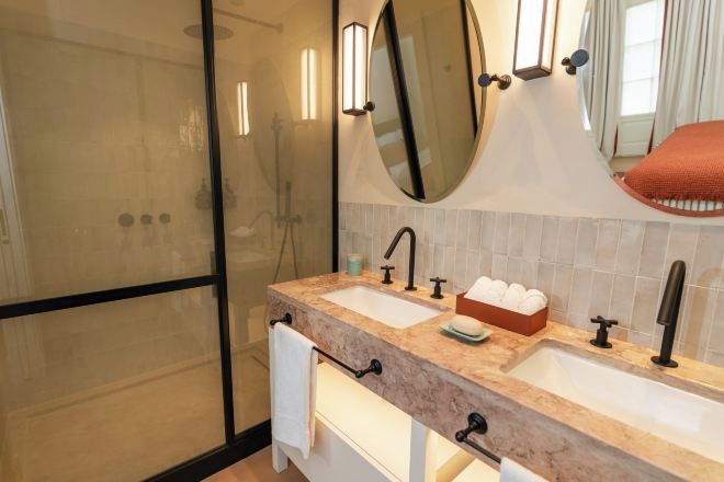 Un bany amb un doble lavabo, un mirall gran i un espai de banyera amb vidre.