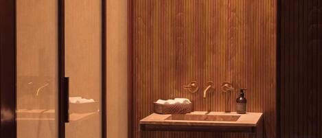 A bathroom with a wooden wall, a sink, and a bottle of soap.