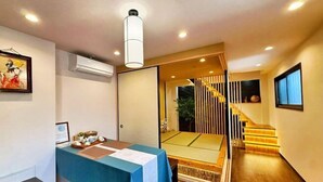 A modern hotel room with a wooden floor, a blue table with a white tablecloth, a framed picture on the wall, and a staircase leading to a balcony. - Seishukugawa (Osaka)