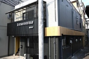 A building with a black storefront and a wooden door. - Seishukugawa (Osaka)