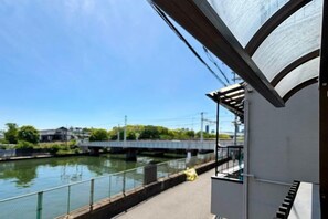 A view of a river with a bridge, a walkway, and a building with a covered area. - Seishukugawa (Osaka)