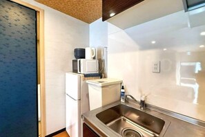 A compact kitchen with a stainless steel sink, a microwave, and a refrigerator. - Seishukugawa (Osaka)