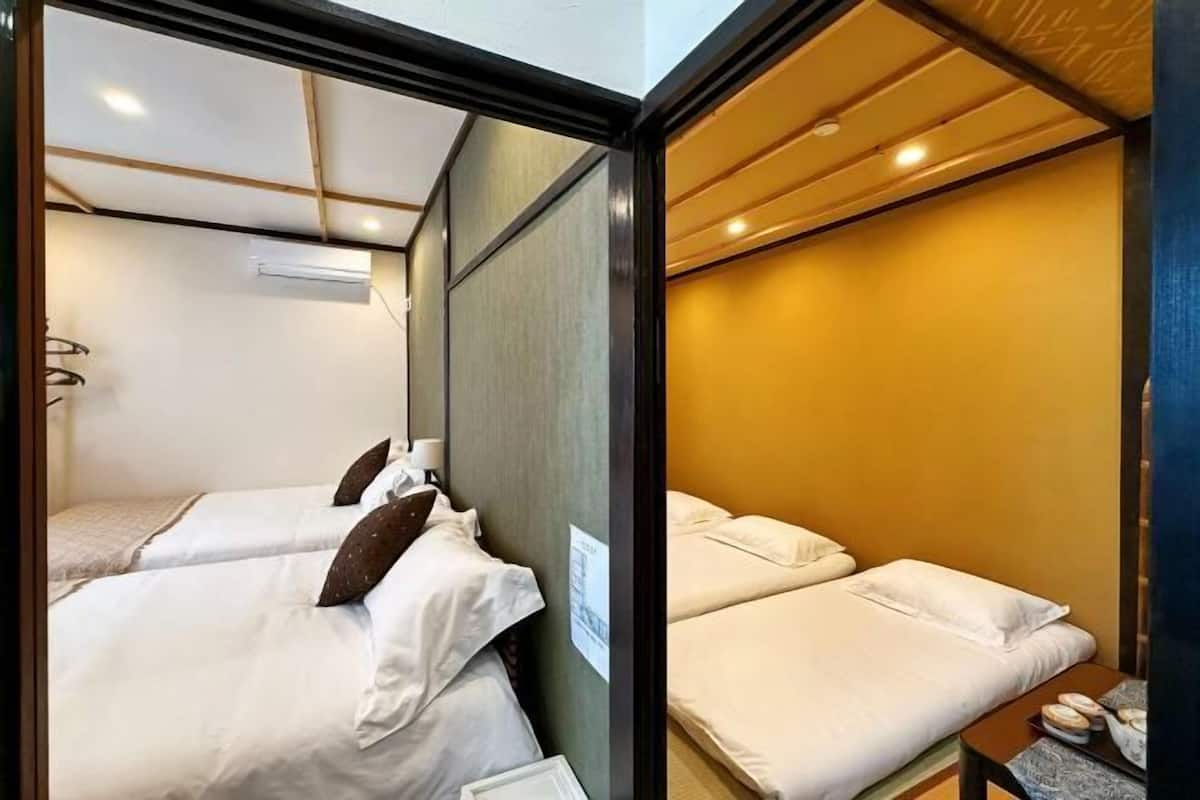 A hotel room with two beds, a wooden headboard, and a small table with a lamp.