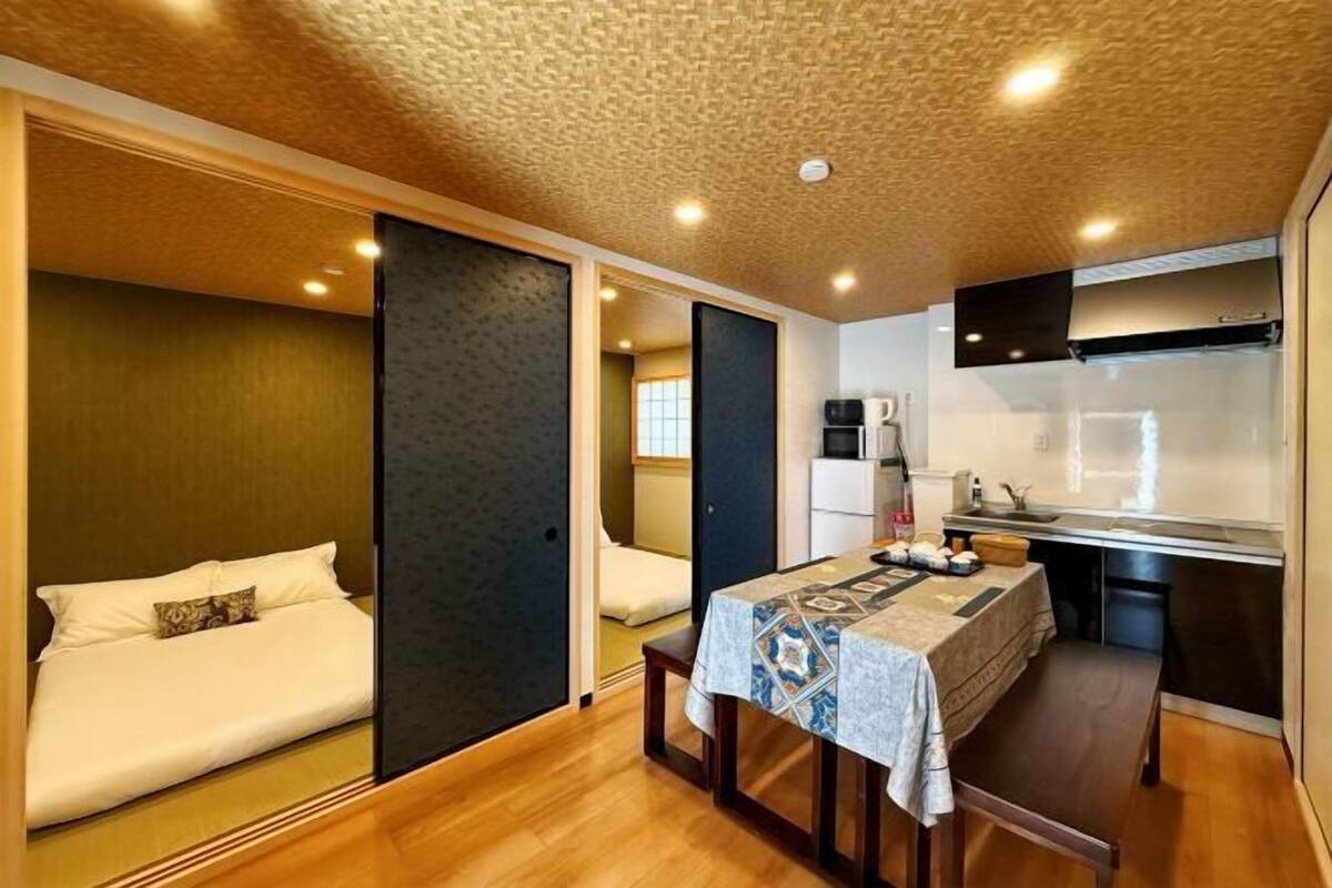 A compact hotel room with a bed, a small dining table, and a kitchenette.