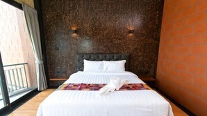 A hotel room with a bed, a brick wall, and a window with curtains. - Windmill Place Khaoyai (Pak Chong)