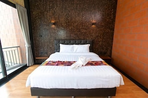 Habitación de hotel con cama, pared de ladrillo y ventana con cortinas.