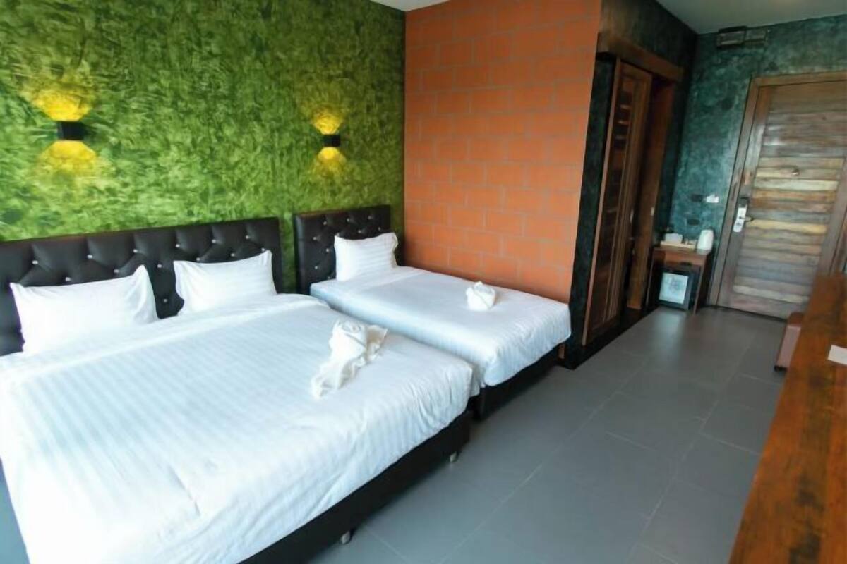 A hotel room with two beds, a brick accent wall, and a green textured wall.