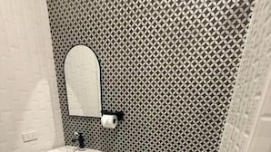 Un baño con piso estampado, un lavamanos blanco y un inodoro.