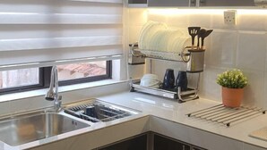 A modern kitchen with a built-in dishwasher, a sink, and a dish drying rack. - RR Homestay D' Awana Kijal (Kijal)