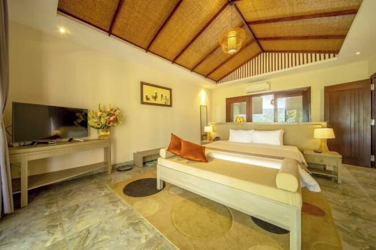 A bedroom with a bed, bedside tables, a TV, and a ceiling fan.