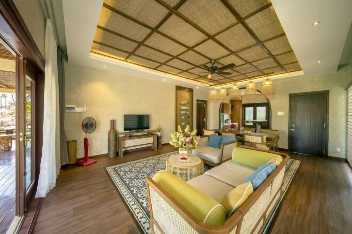 A spacious living area with a ceiling fan, a television, and a sofa with cushions.