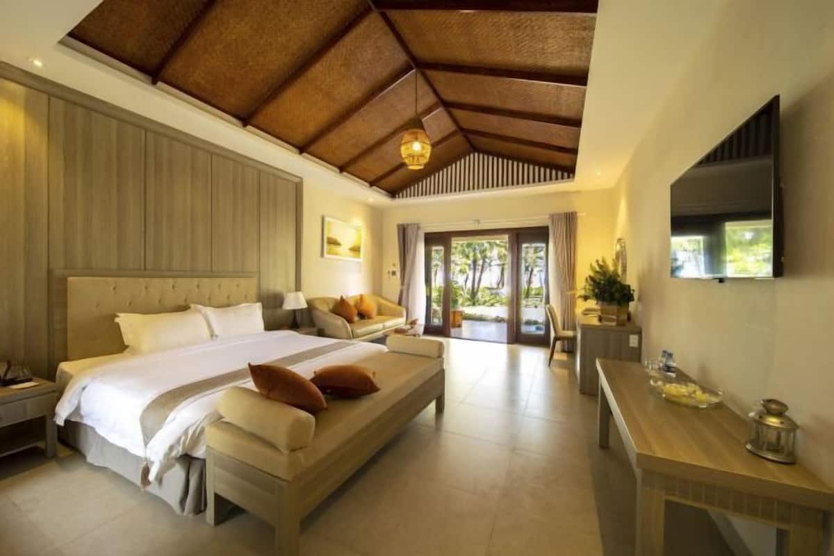 A bedroom with a large bed, a sofa, a desk, and a TV.