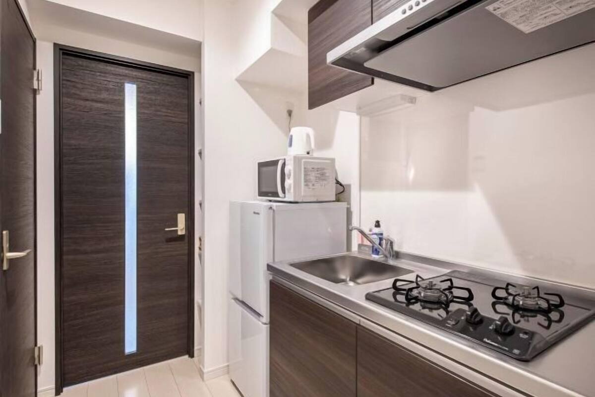 A compact kitchen with a microwave, refrigerator, and gas stove.