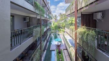 A narrow courtyard with a central water feature, surrounded by balconies with plants and outdoor furniture.