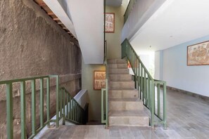 A staircase with green railings, a stone wall, and framed artwork on the walls. - Sans Vibes Residence and Villa Cemagi (Bali)
