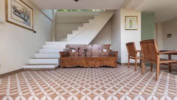 A staircase leading to an upper floor, a wooden bench, and a dining area with chairs.
