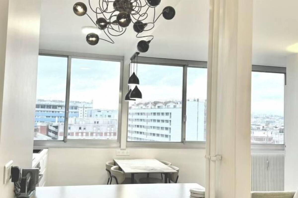 A modern room with large windows, a dining table, and a unique ceiling light fixture.