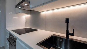 A modern kitchen with a black sink, stainless steel countertop, and a built-in range hood. - Apartement Choisy (Paris)