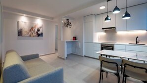 A modern kitchen with pendant lighting, a dining area with chairs, and a sofa. - Apartement Choisy (Paris)
