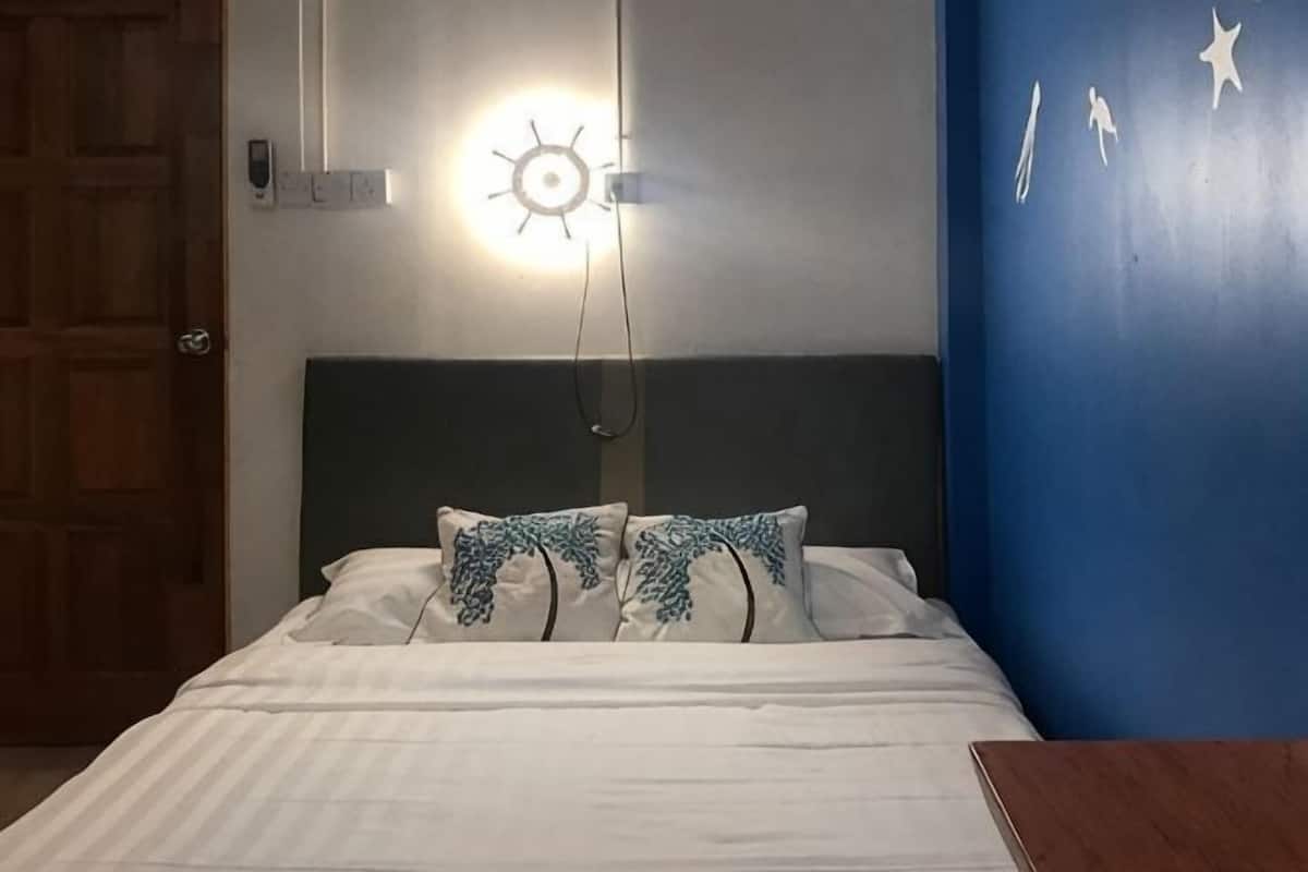 Una cama con ropa de cama blanca, cabecera verde y almohadas estampadas.