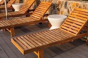 Wooden lounge chairs with white cushions and a stone wall in the background. - Apec Mandala Chambay Mui Ne - Oceanic Studio (Phan Thiet)