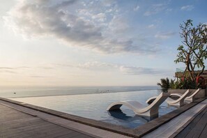 An infinity pool with lounge chairs, a wooden deck, and a view of the sea. - Apec Mandala Chambay Mui Ne - Oceanic Studio (Phan Thiet)