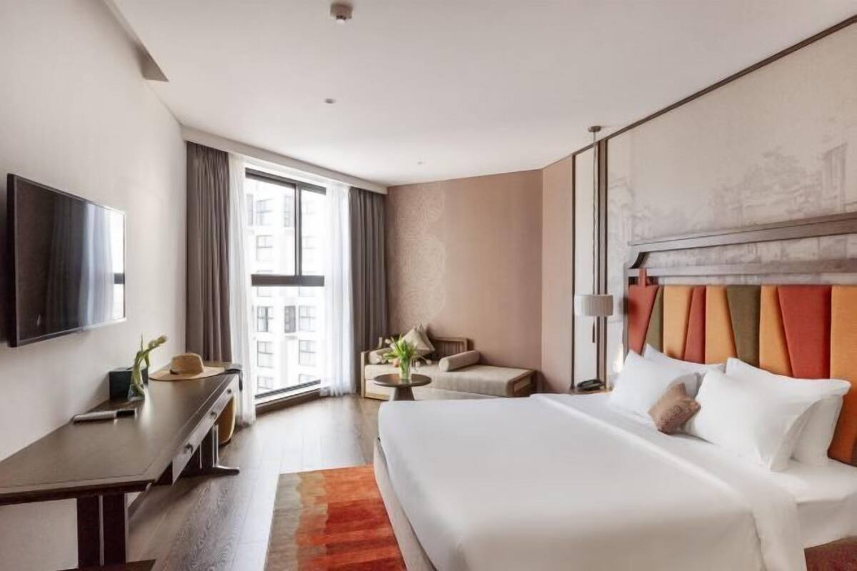 Ein modernes Hotelzimmer mit einem großen Bett, einem Flachbildfernseher, einem Schreibtisch und einer Sitzecke.