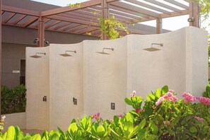 A row of outdoor shower cubicles with a pergola overhead. - Apec Mandala Chambay Mui Ne - Oceanic Studio (Phan Thiet)
