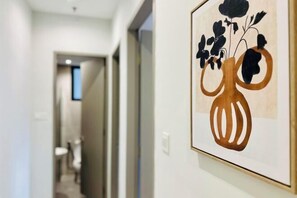 A hallway with a framed artwork of a vase with flowers on the wall.
