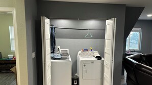 A laundry room with a washing machine, dryer, and a small table with cleaning supplies. - Superb 4-bedroom house with AC in Whitney (Whitney)