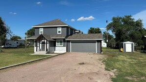 A two-story house with a covered porch, a garage, and a small shed. - Superb 4-bedroom house with AC in Whitney (Whitney)