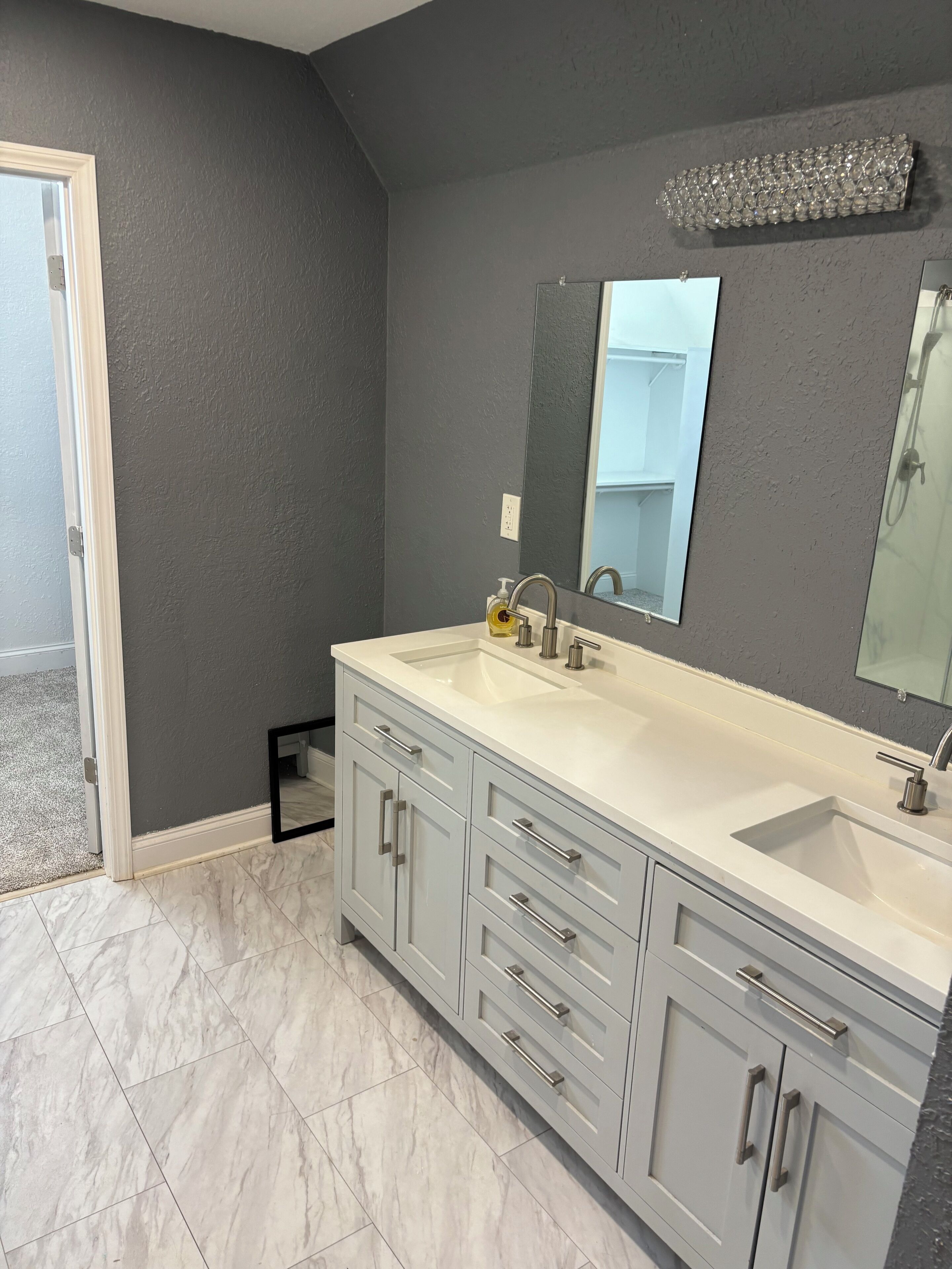 A modern bathroom with a double sink vanity, a large mirror, and marble flooring.