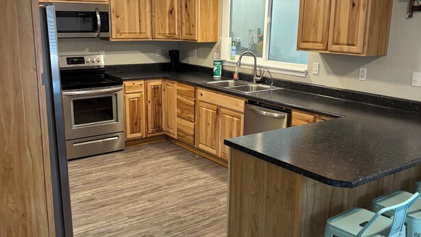 A modern kitchen with wooden cabinets, stainless steel appliances, and a central island with bar stools. - Superb 4-bedroom house with AC in Whitney (Whitney)
