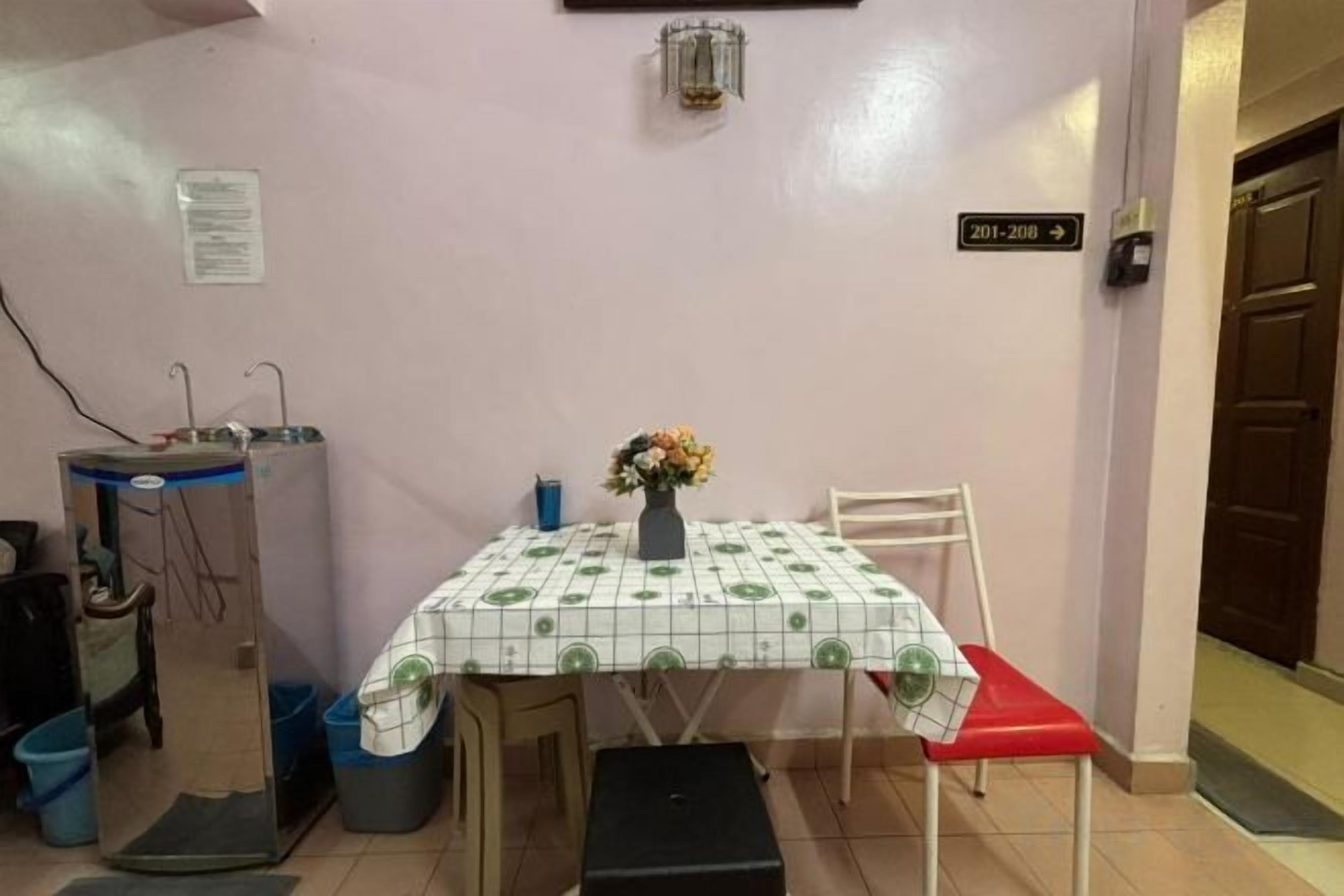 Un pequeño comedor con una mesa, sillas, un florero con flores y un cartel que indica las habitaciones 201 a 208.