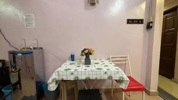 Un pequeño comedor con una mesa, sillas, un florero con flores y un cartel que indica las habitaciones 201 a 208.