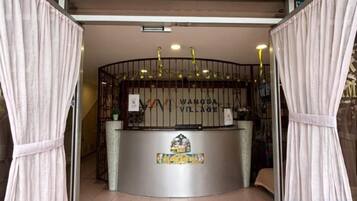A reception desk with a sign that reads 'WANGSA VILLAGE' and a decorative emblem below it.