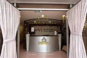 Un comptoir d’accueil avec une enseigne indiquant « WANGSA VILLAGE » et un emblème décoratif en dessous.
